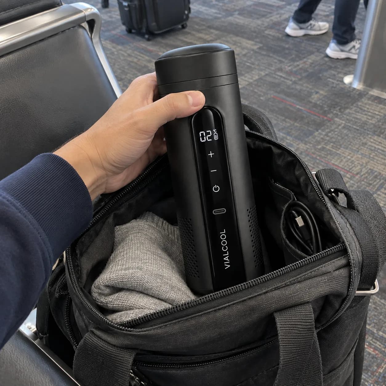 Held over an open tote at an airport gate, display reading 02