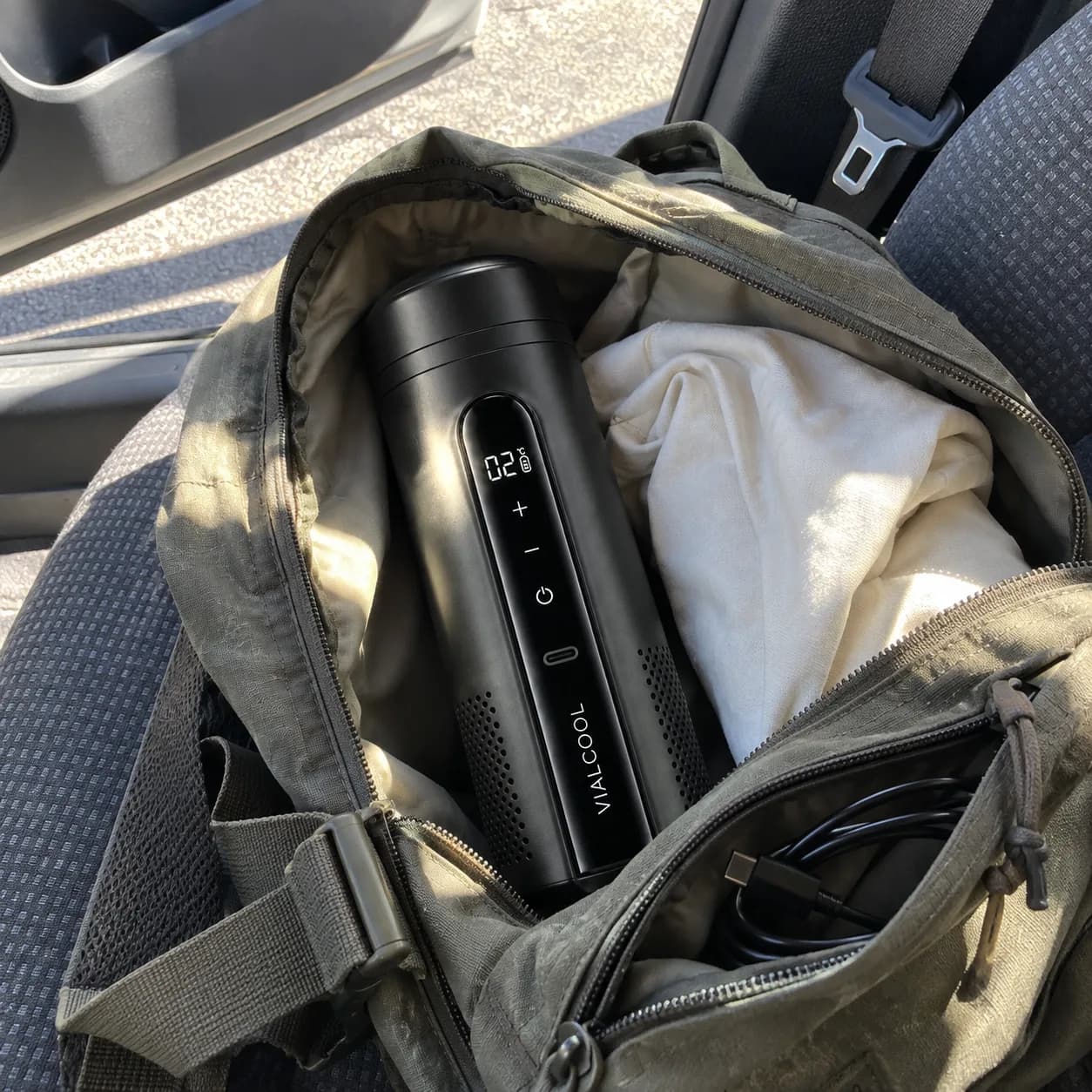 Standing in an open backpack on a car seat next to a USB cable